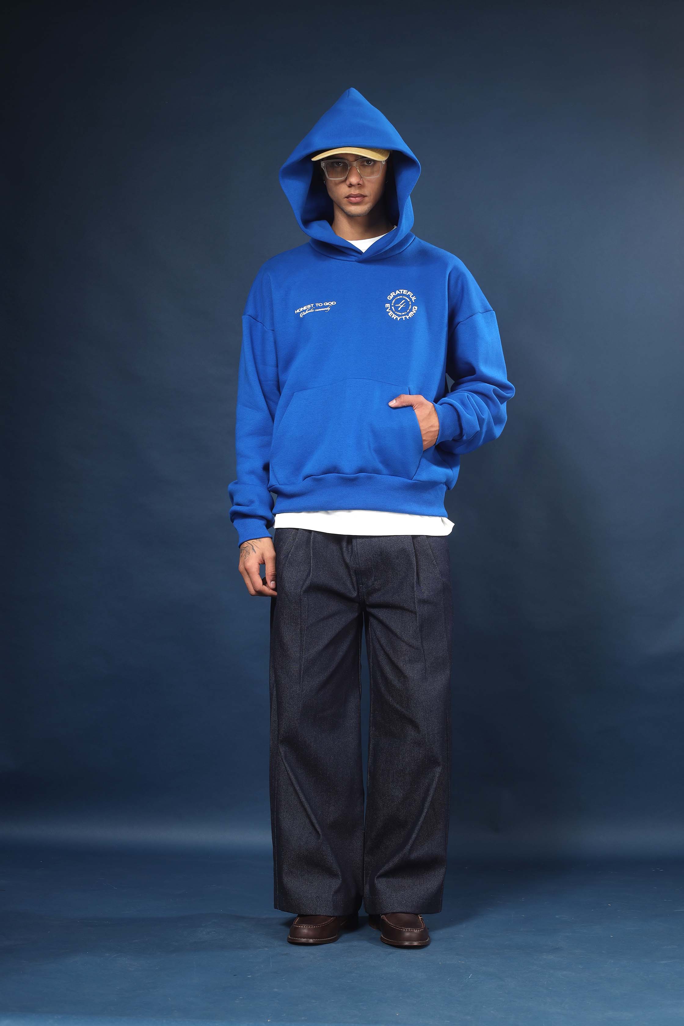 Model wearing Honest to God Cobalt Blue boxy hoodie for a 90s inspired international vibe.