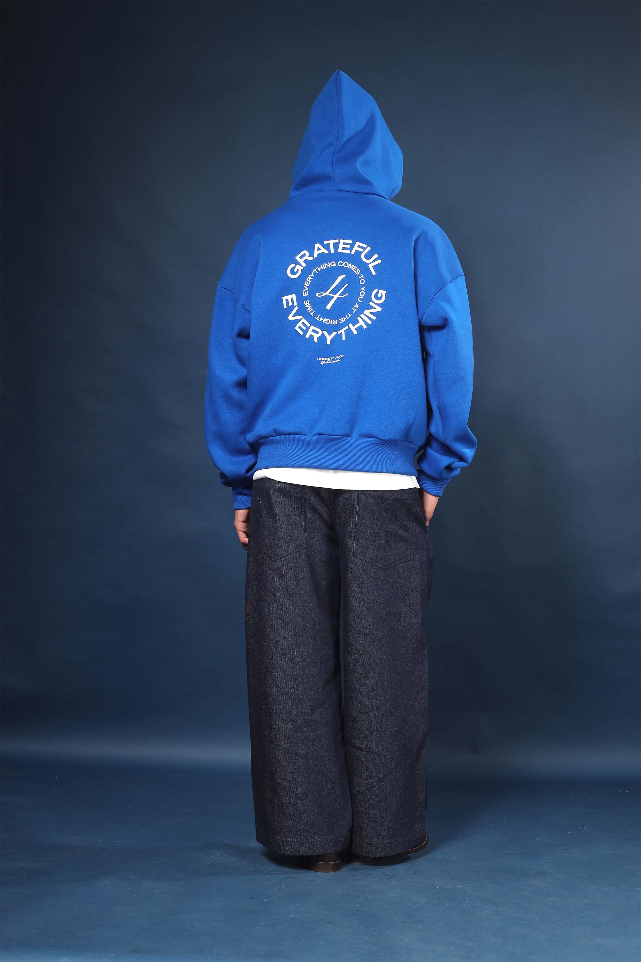 Model wearing Honest to God Cobalt Blue boxy hoodie for a 90s inspired international vibe.